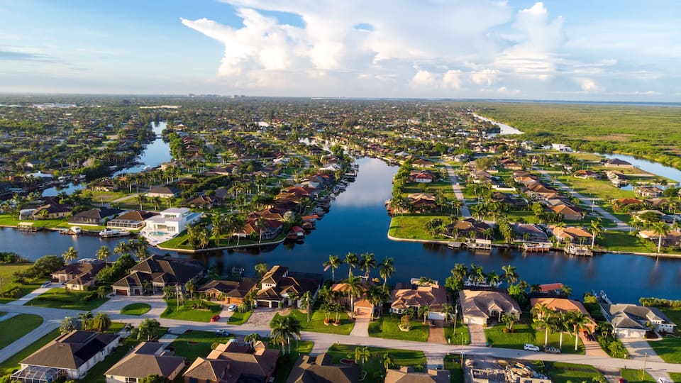 A residential area with houses, a river, and a clear sky.