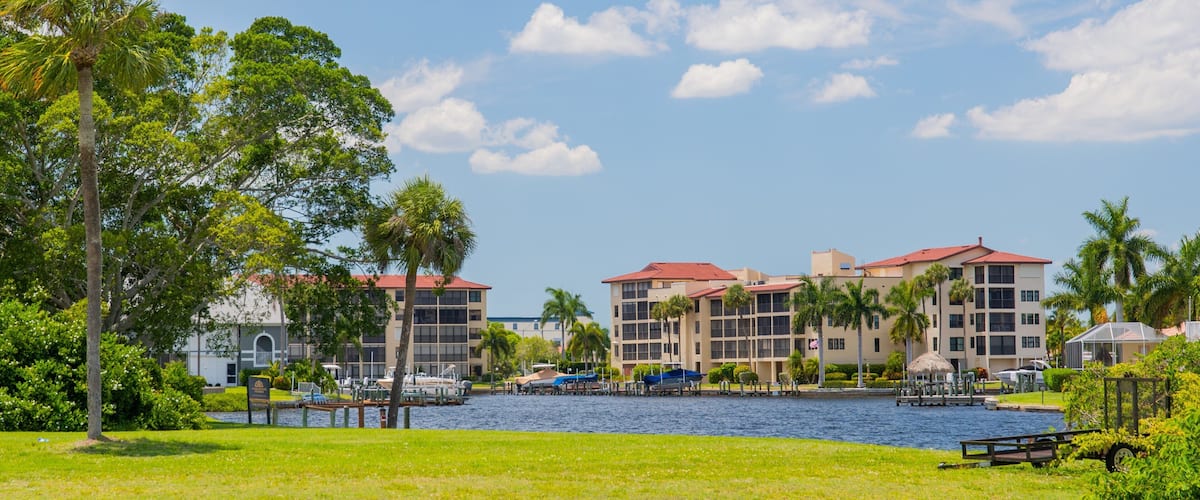 A waterfront resort with multiple buildings, palm trees, and a marina.