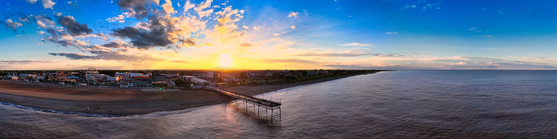 A sunset over a beach with a pier extending into the water.