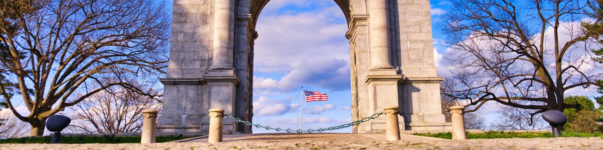 The National Memorial Arch stands with the American Flag blowing in the middle at Valley Forge National Park in Pennsylvania.