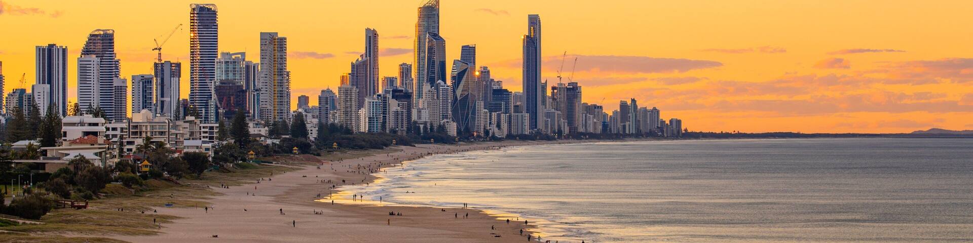 Una playa con gente y el perfil urbano de una ciudad al fondo.