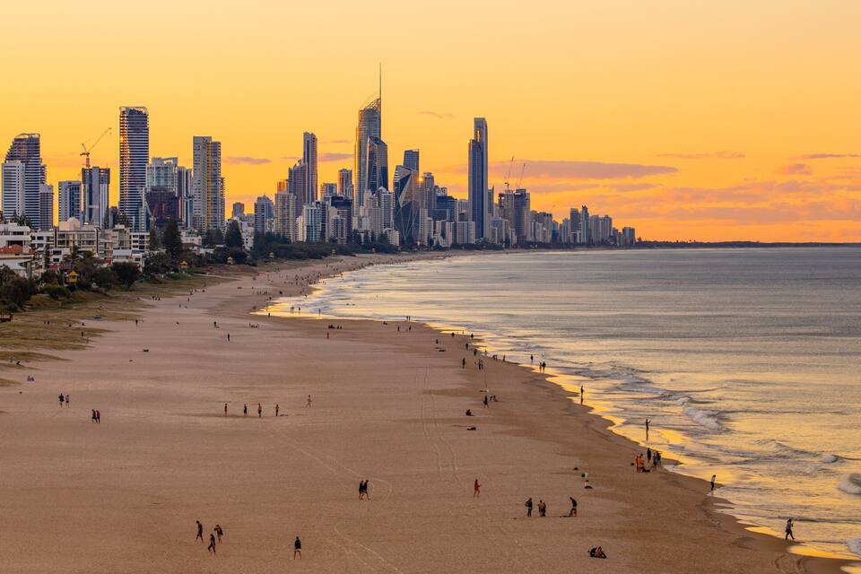 A beach with people and a city skyline in the background.