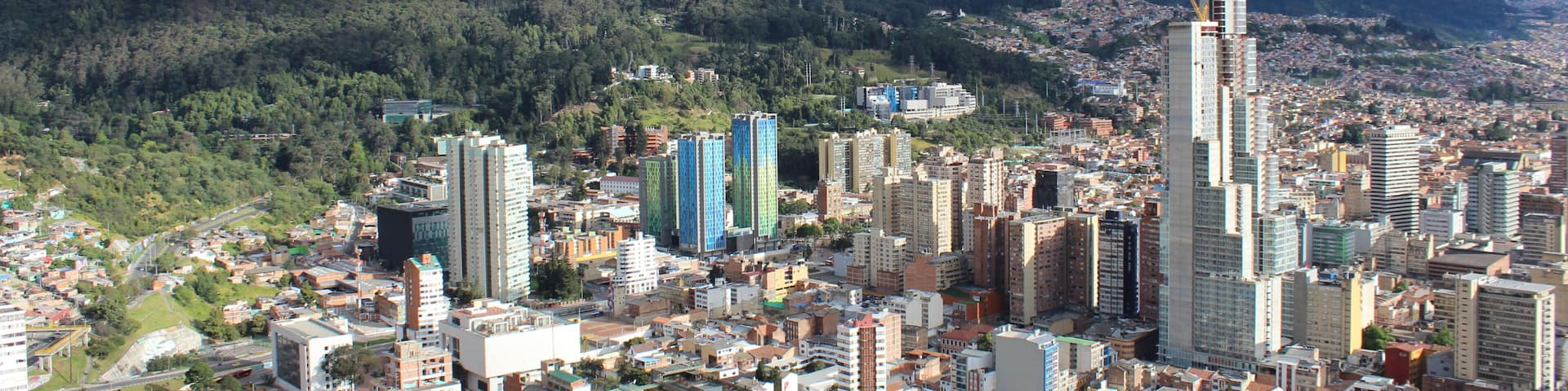 A cityscape with a prominent skyscraper, dense urban buildings, and a mountain in the background.