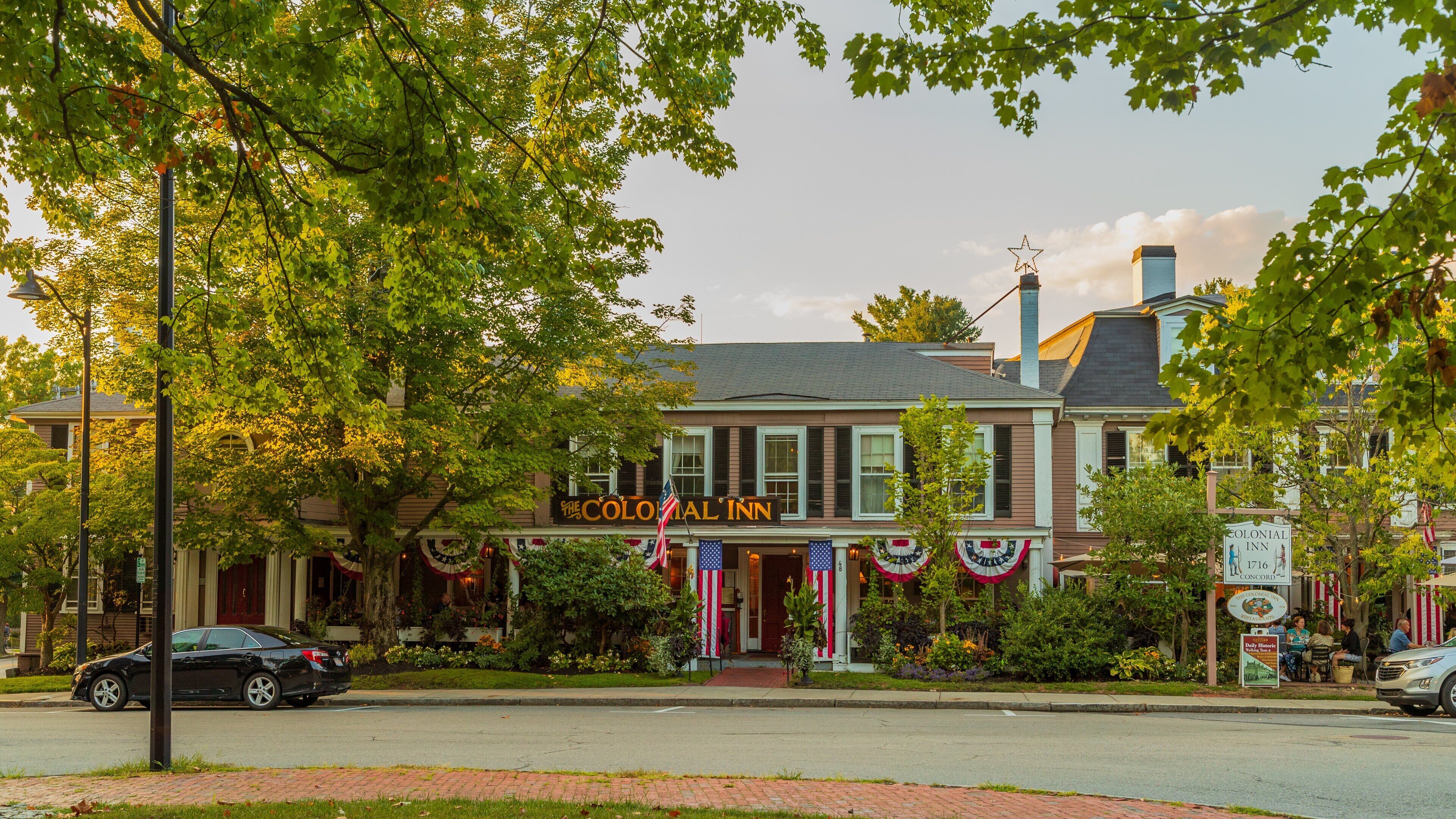 A historic building with a Colonial Inn sign, surrounded by trees and a brick sidewalk.