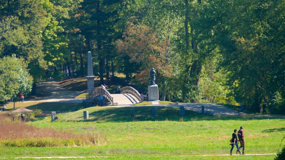 A park with a statue, a bridge, and a grassy area.