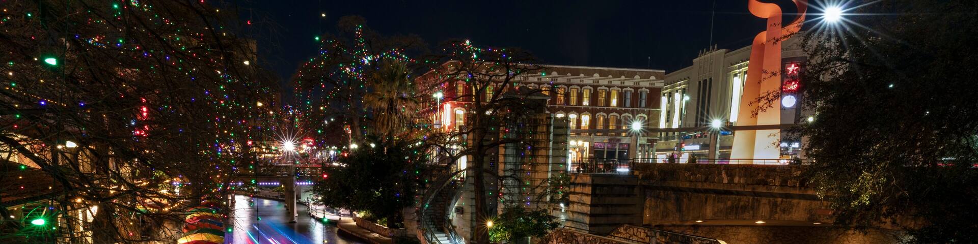 A nighttime cityscape with illuminated streets, a bridge, and a large sculpture.