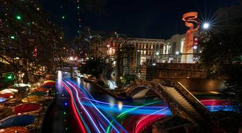 A nighttime cityscape with illuminated streets, a bridge, and a large sculpture.