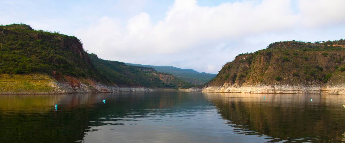 A calm river with rocky banks and hills in the background.