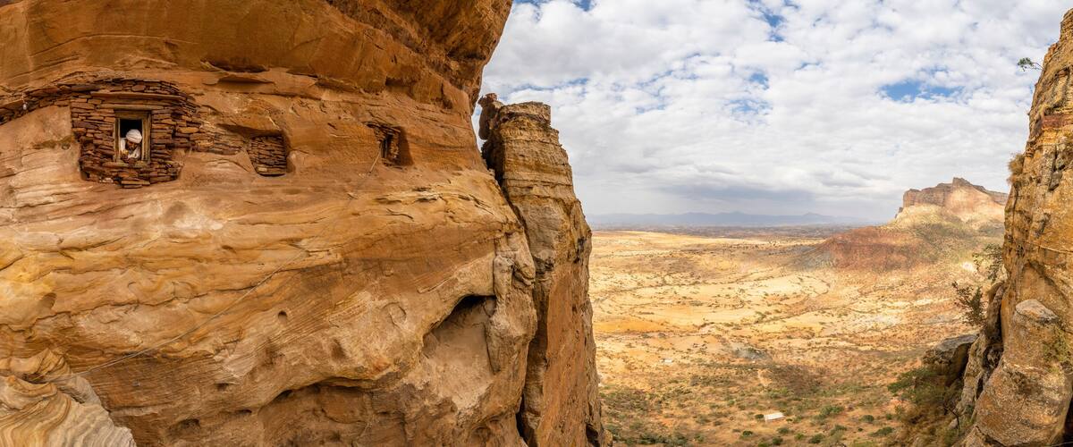 Aerial panoramic by drone of priest looking out from Abuna Yemata Guh rock-hewn church, Gheralta Mountains, Tigray region, Ethiopia