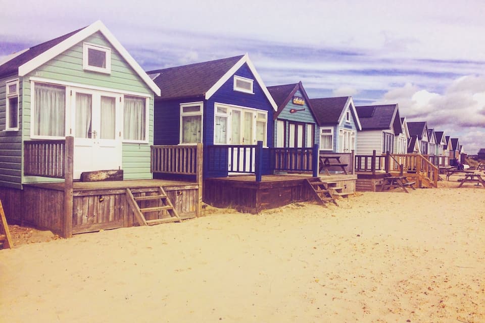 A row of beach houses with wooden decks and railings.