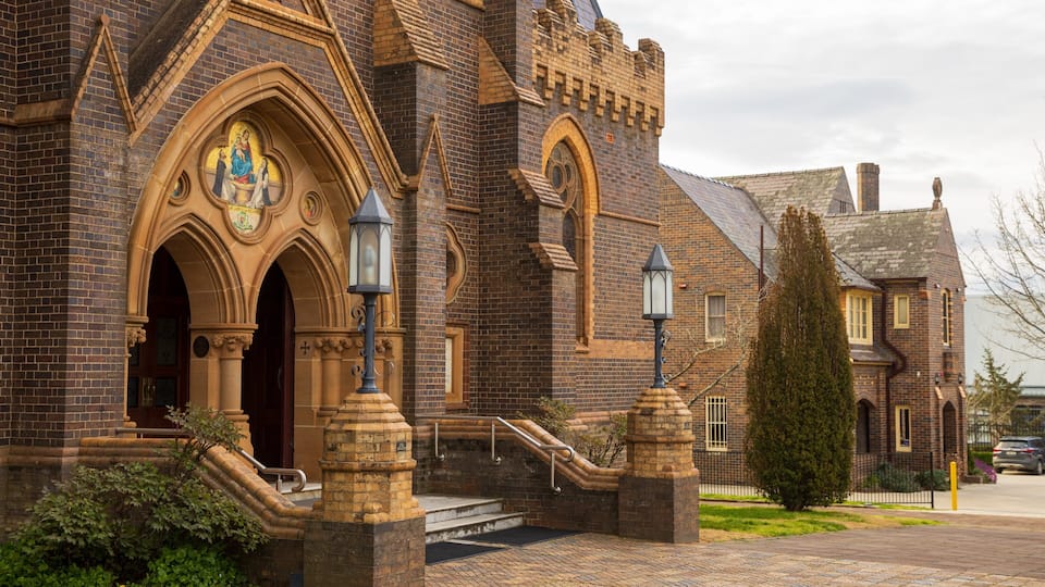 A historic church with Gothic architecture, brick walls, and a prominent stained glass window.