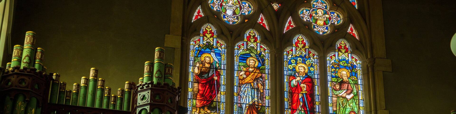 A stained glass window with religious figures and inscriptions.