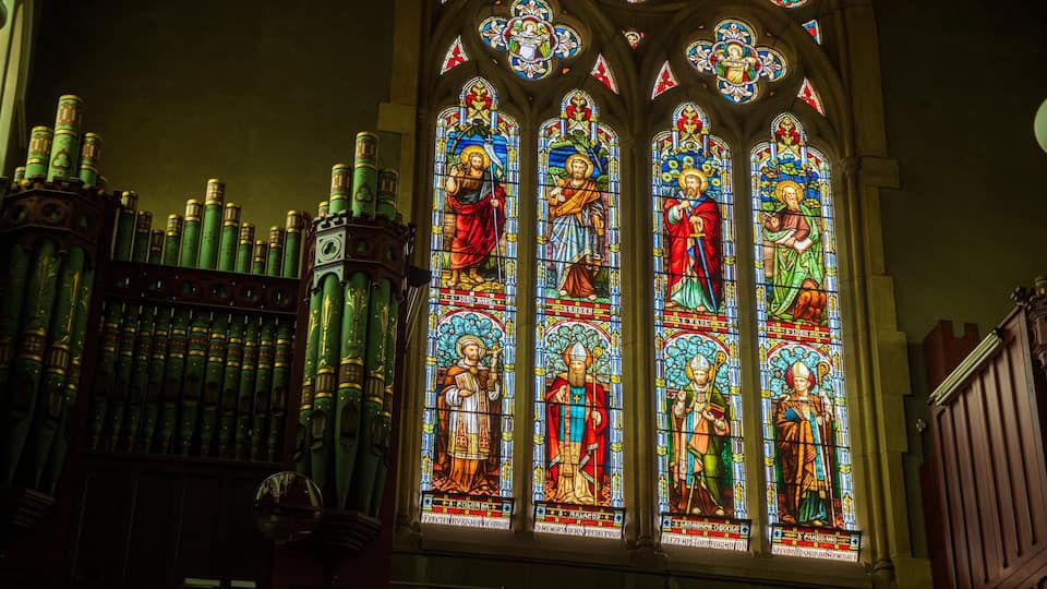 A stained glass window with religious figures and inscriptions.