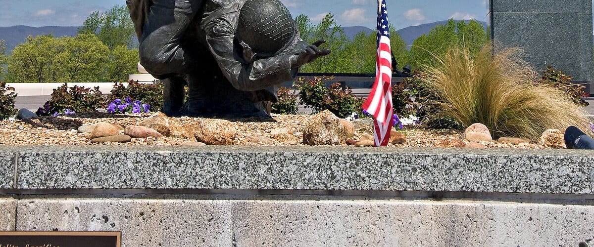 The National D-Day Memorial is an awe-inspiring tribute to the D-Day Invasion, the largest amphibious military landing the world has ever seen. Bedford, Virginia, was chosen as the location of the memorial because the community of Bedford suffered the highest per-capita D-Day losses in the nation.
The memorial is spread over 88 acres and is divided into patterns which represent the various stages or aspects of the invasion.
The centerpiece of the memorial is the Victory Plaza arch, which can be seen for miles. The arch contains a single word, Overlord, referring to Operation Overlord, the code name of the Battle of Normandy. The arch is crowned with five chiseled elements designed to resemble the roofs of houses seen by airborne troops as they passed over the Normandy countryside on the eve of D-Day. The chiseled elements are painted in a black and white pattern, just like the stripes painted on the wings of Allied aircraft.