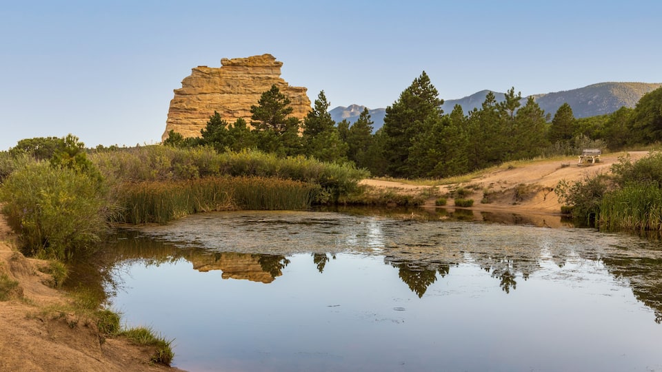A river reflecting a rock formation and trees.