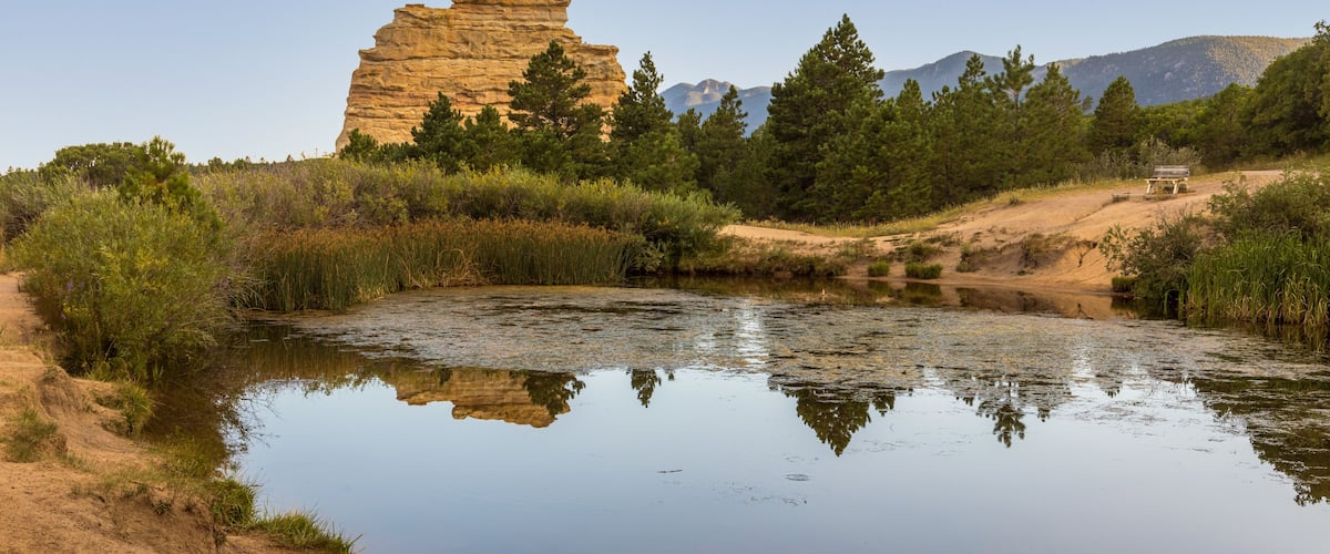 A river reflecting a rock formation and trees.