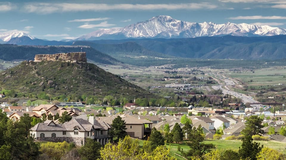 A town with a historic fort on a hill, surrounded by mountains and a valley.