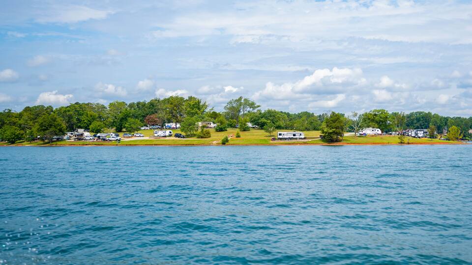 A lake with a row of houses and RVs on the shore.
