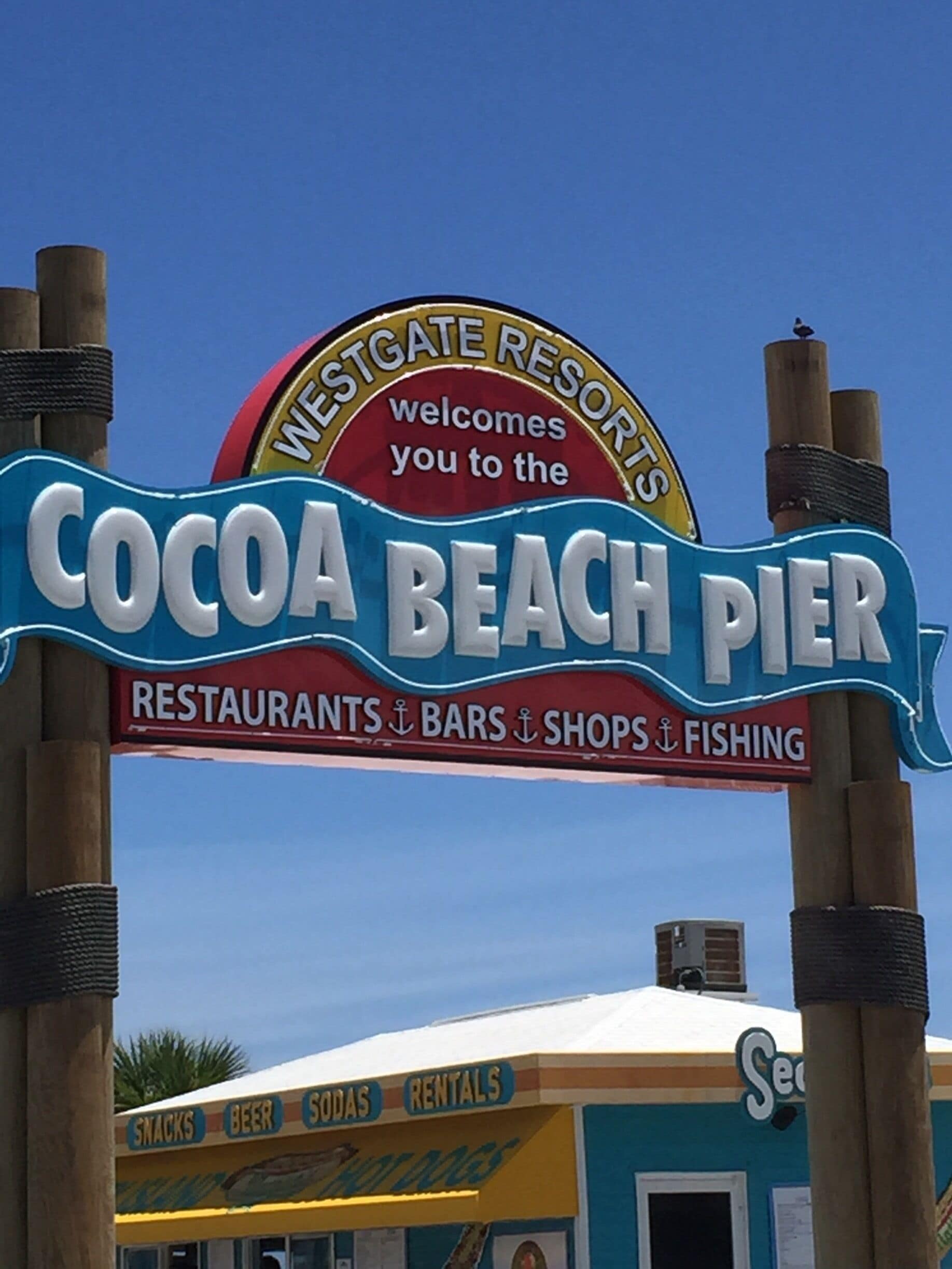A sign for Cocoa Beach Pier at Westgate Resorts, featuring restaurants, bars, shops, and fishing.
