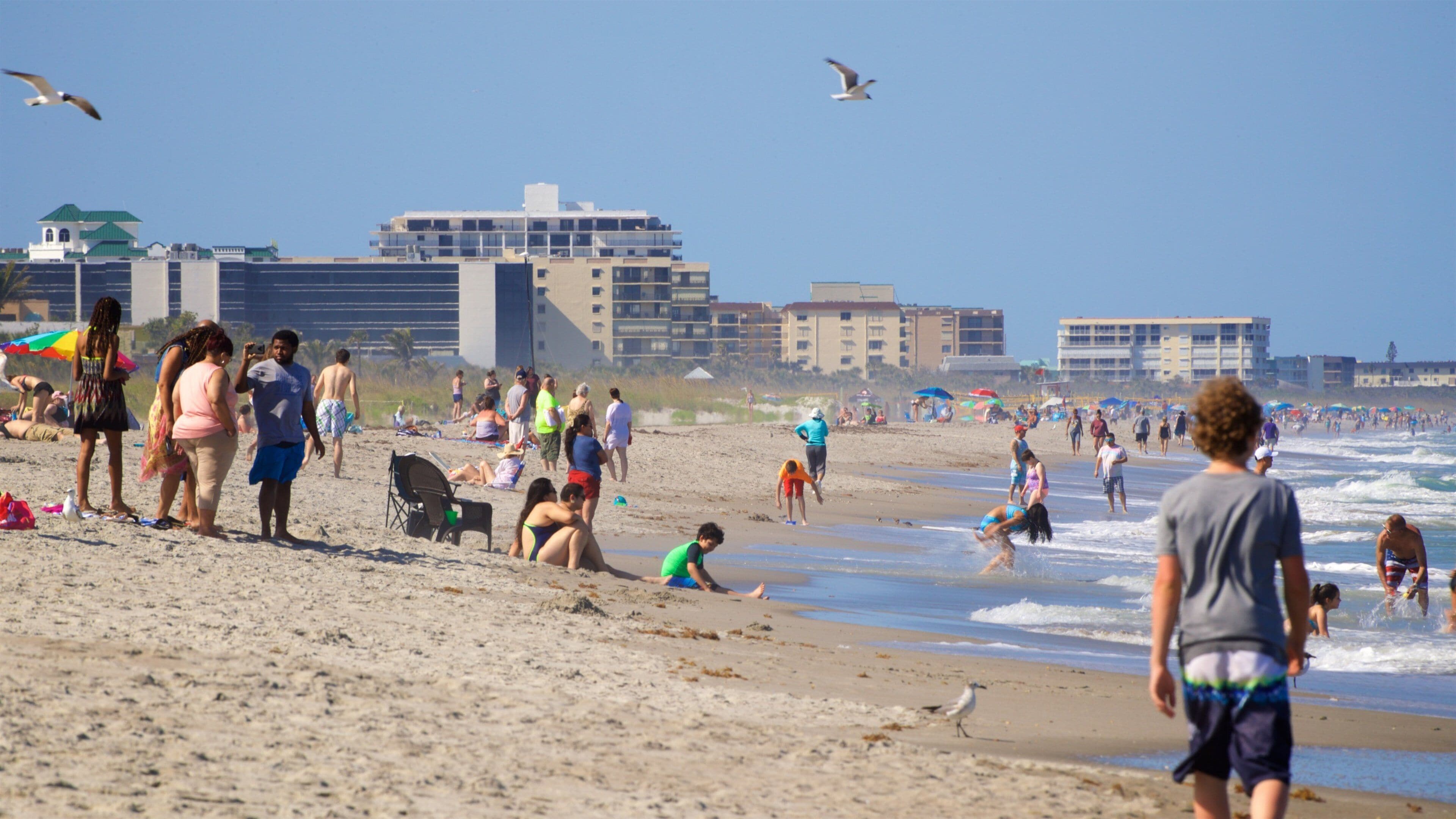 Cocoa Beach which includes a sandy beach and general coastal views as well as a small group of people
