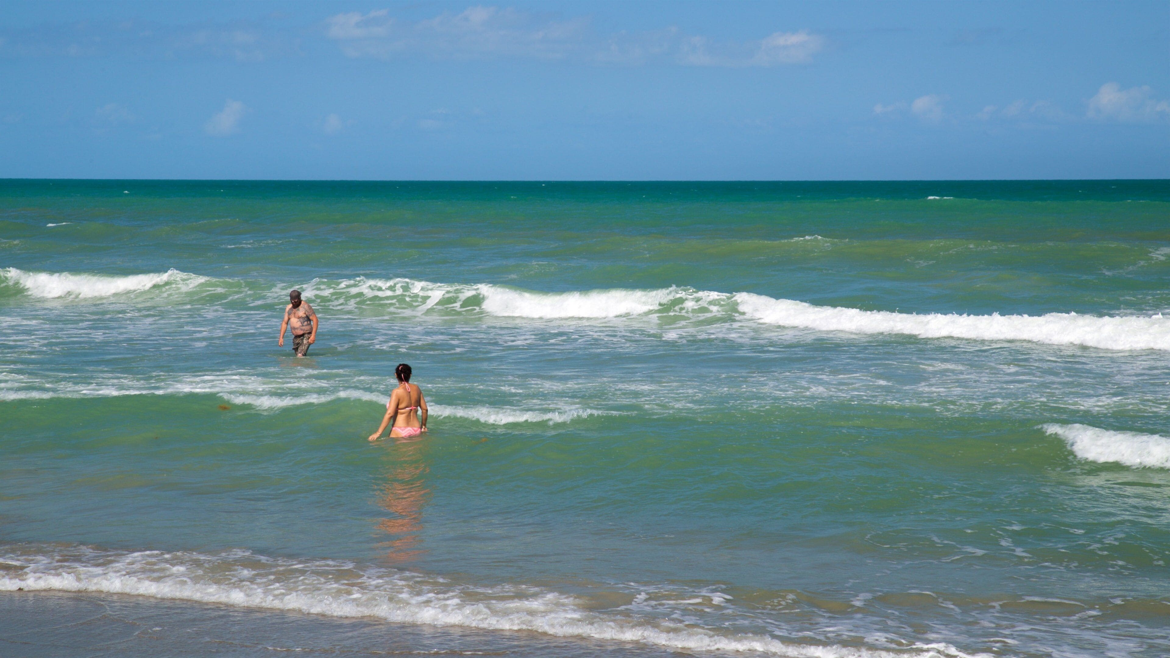 A beach with clear turquoise water and gentle waves.