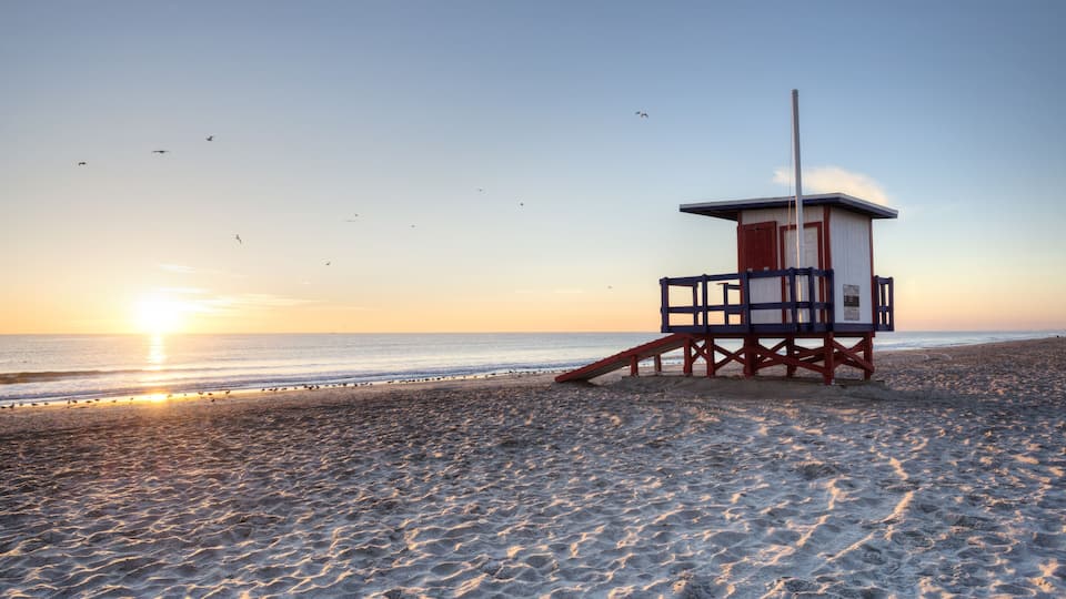 A lifeguard tower on a beach at sunset.