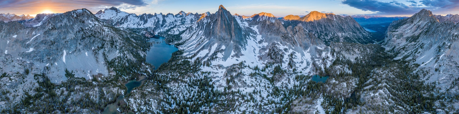 A mountain range with snow-covered peaks and a lake at its base.