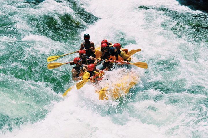 Un grupo de personas en un bote inflable amarillo navega por rápidos turbulentos.