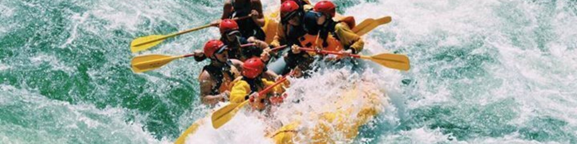 Un grupo de personas en un bote inflable amarillo navega por rápidos turbulentos.