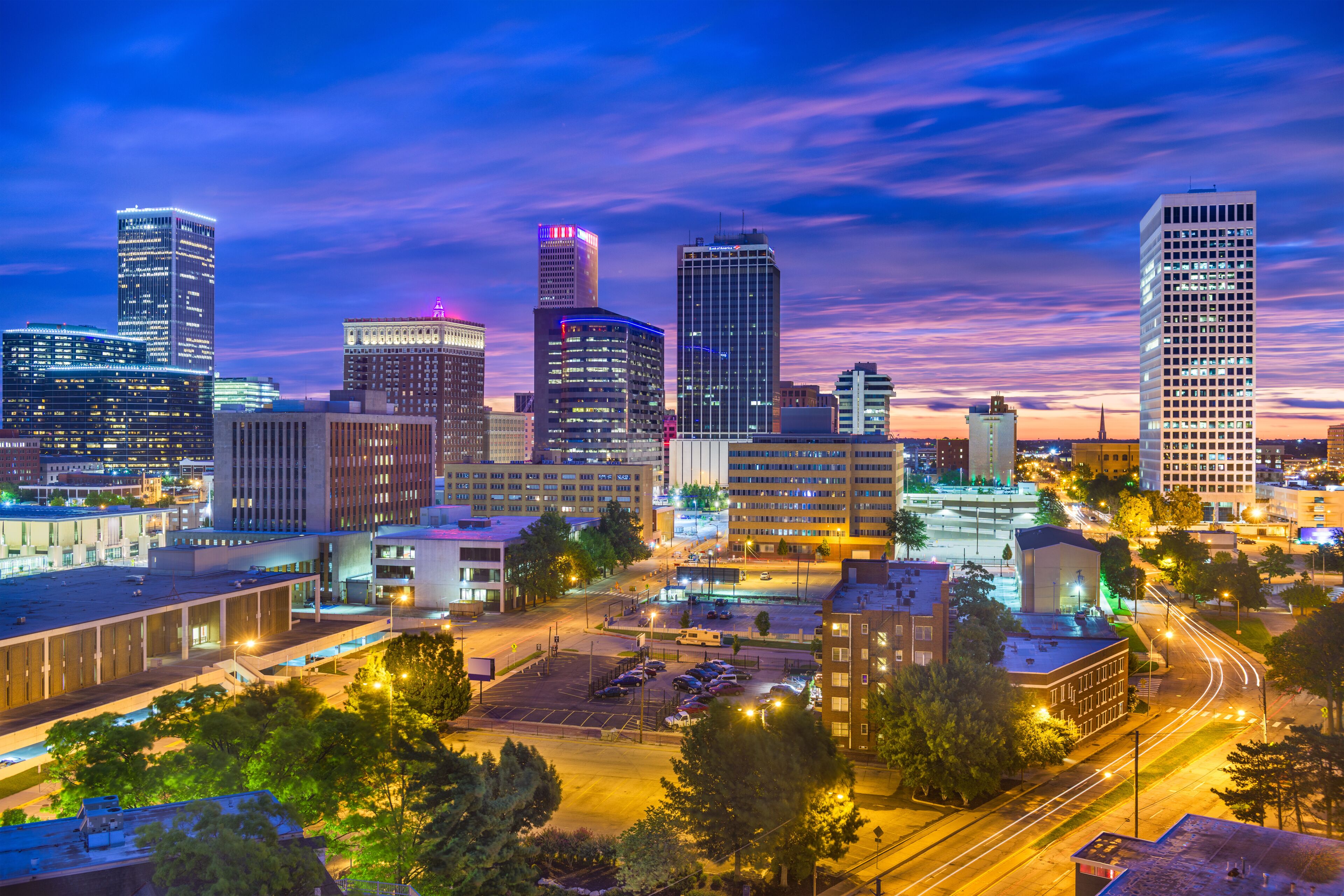 A city skyline with illuminated buildings and a parking lot.