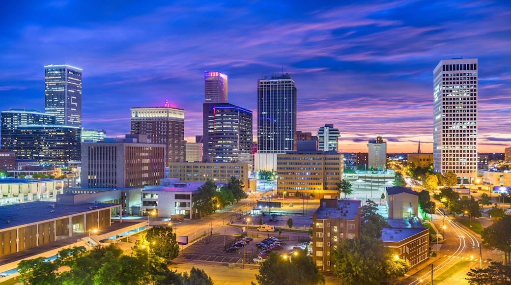 A city skyline with illuminated buildings and a parking lot.