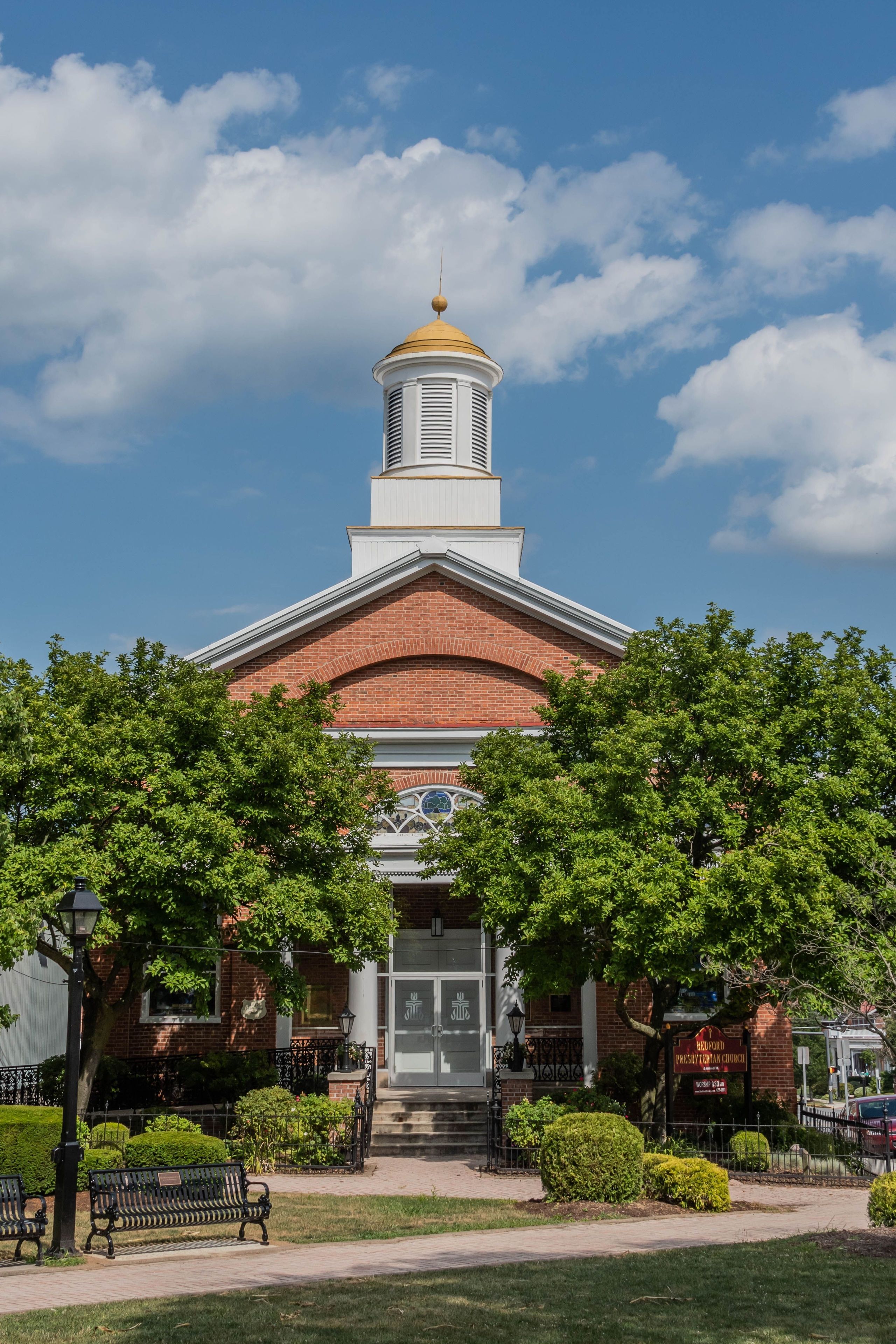 A brick building with a white steeple and a golden dome.