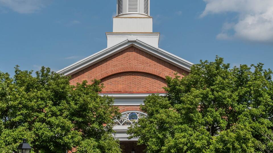 A brick building with a white steeple and a golden dome.