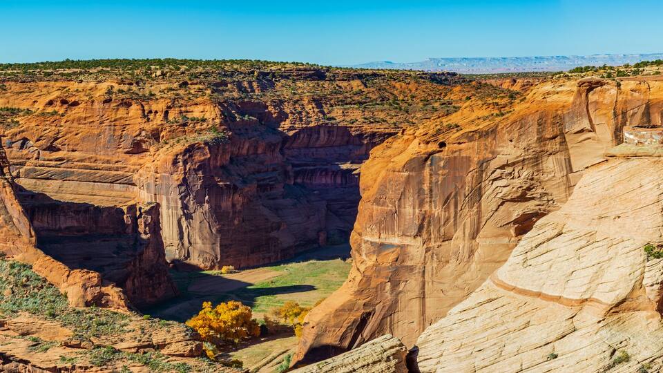 A canyon with layered rock formations and sparse vegetation.