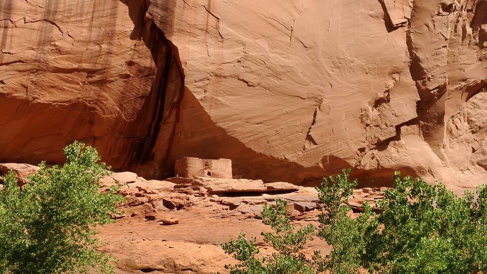 A canyon with red rock formations and green shrubs.