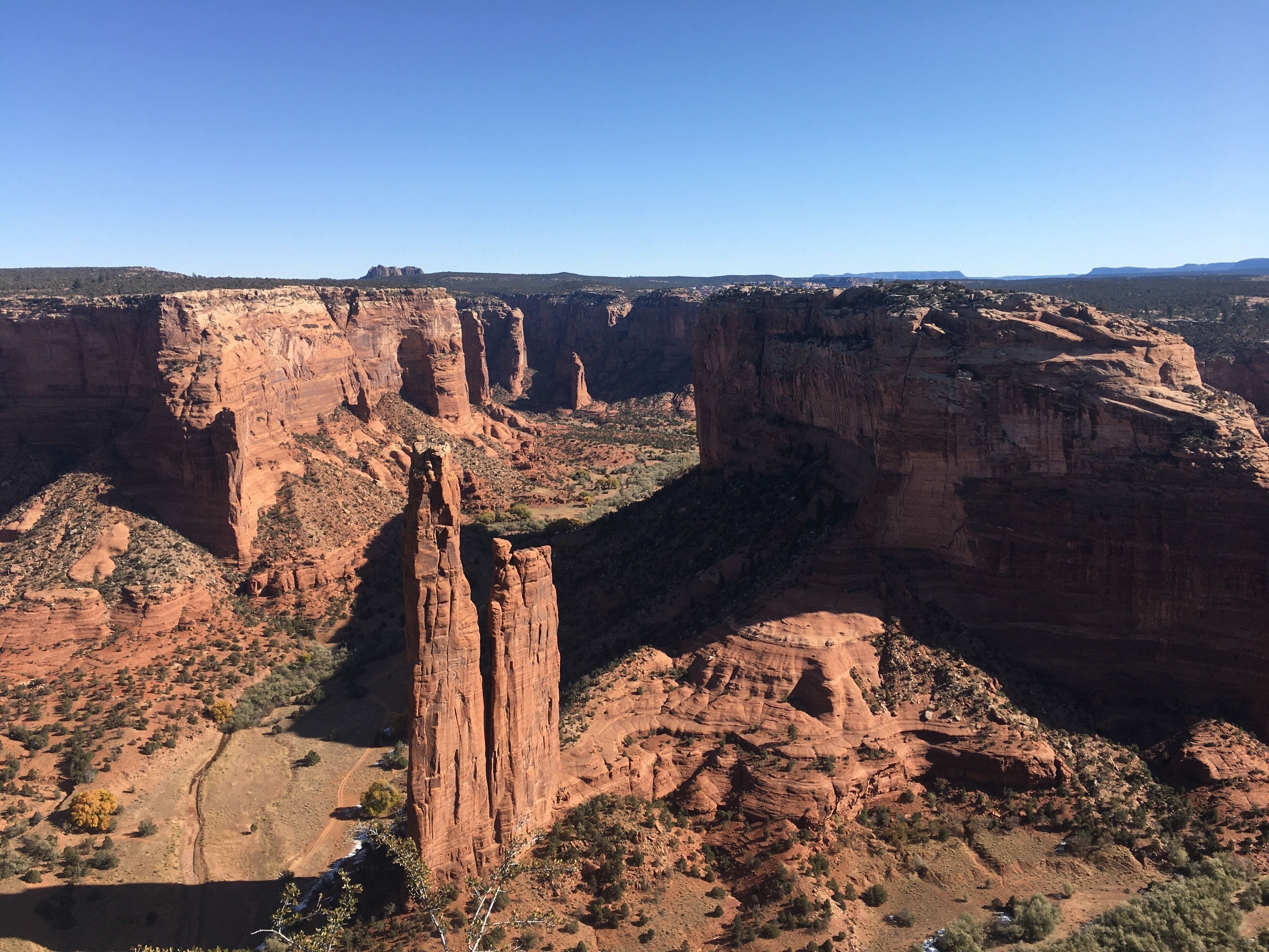 A canyon with prominent red rock formations and sparse vegetation.