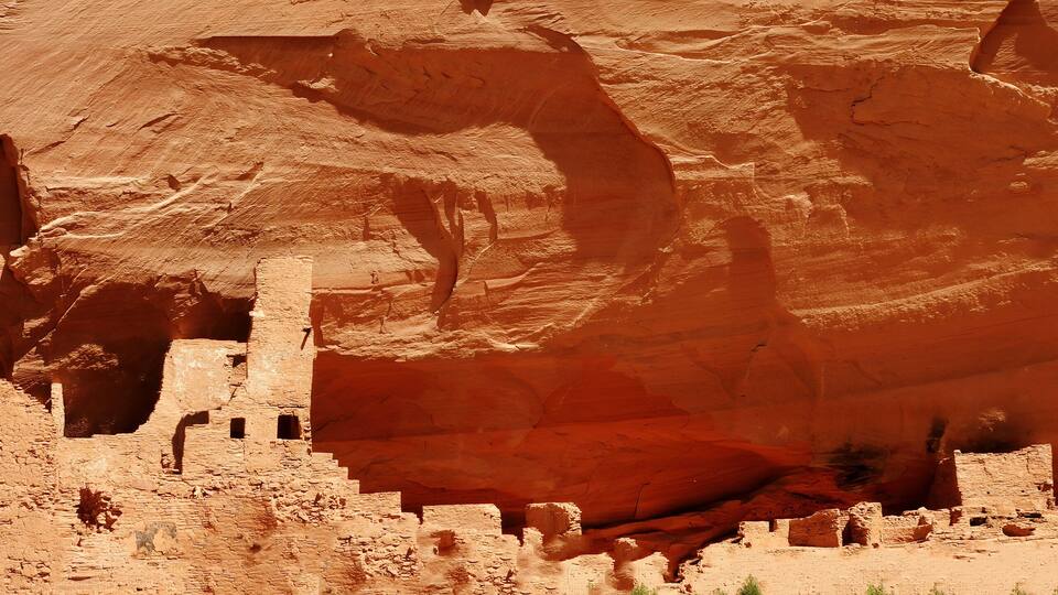 Ancient cliff dwellings carved into a red rock canyon.