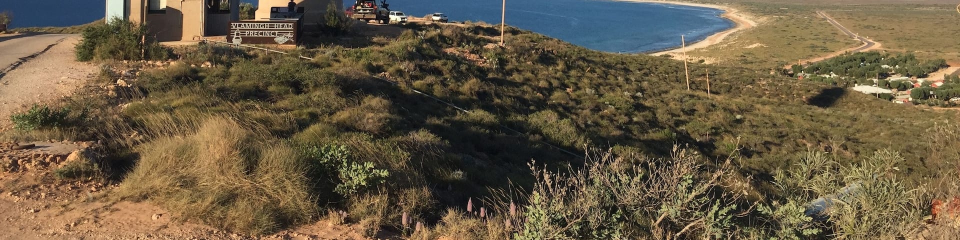Un phare, un petit bâtiment et un paysage côtier sous un ciel dégagé.