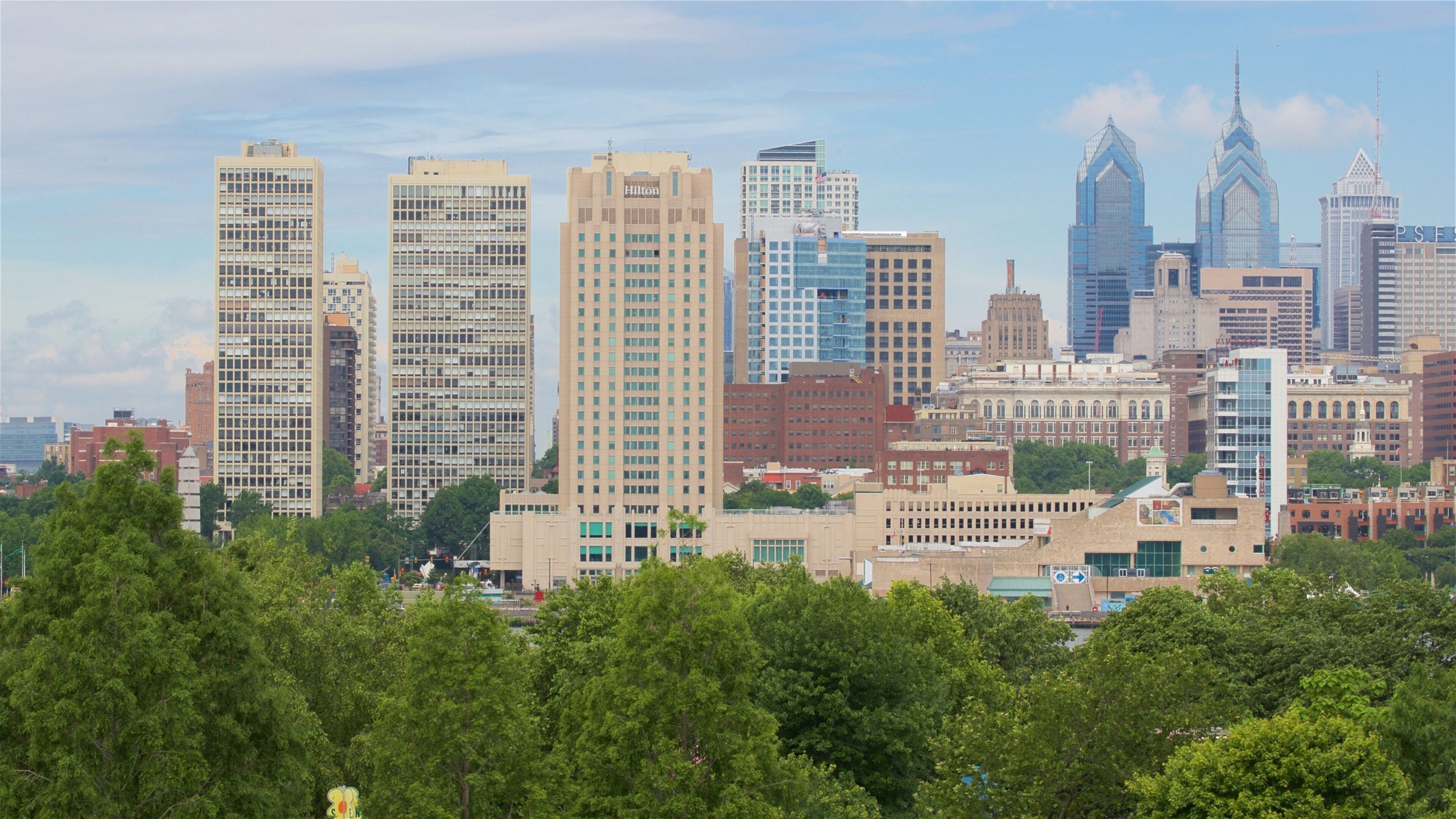 A city skyline with various high-rise buildings, including a Hilton hotel.