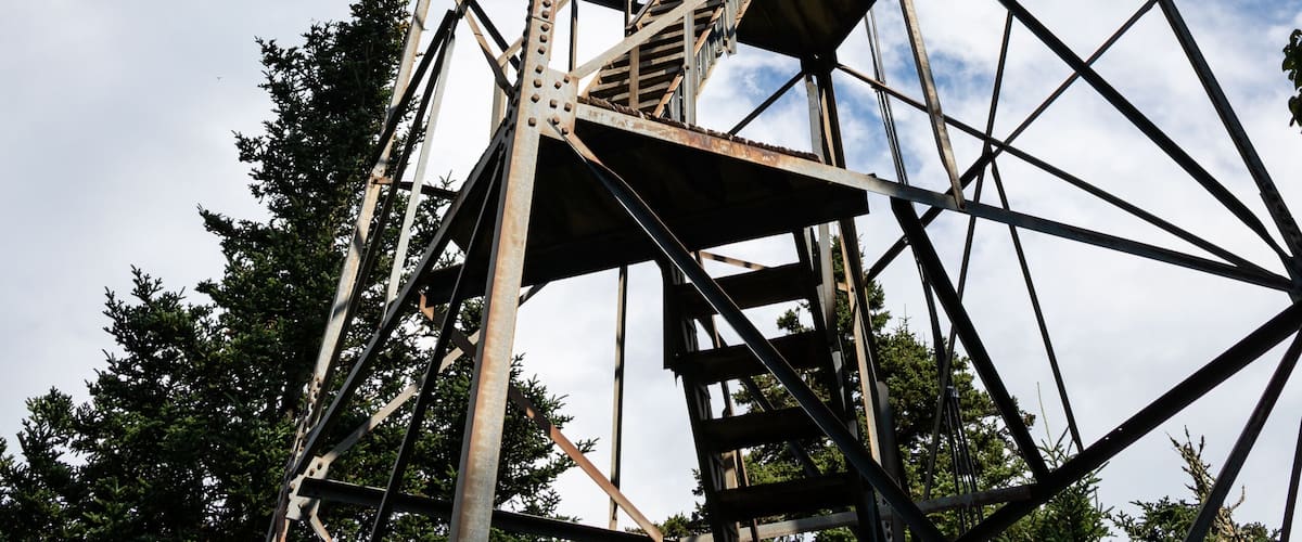 A tall metal tower with a staircase against a partly cloudy sky.