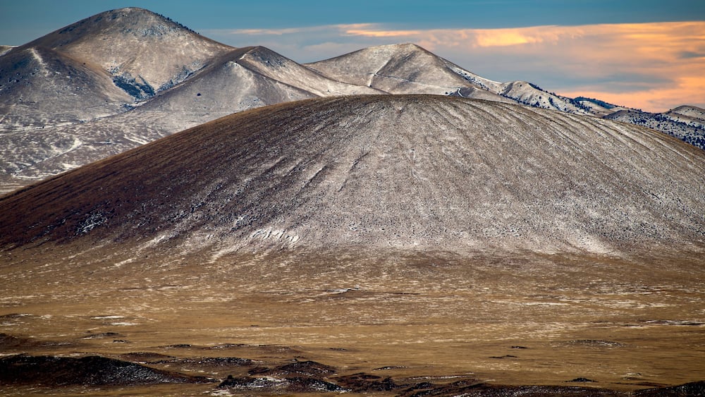 A mountainous landscape with a prominent peak in the foreground and snow-capped mountains in the background.
