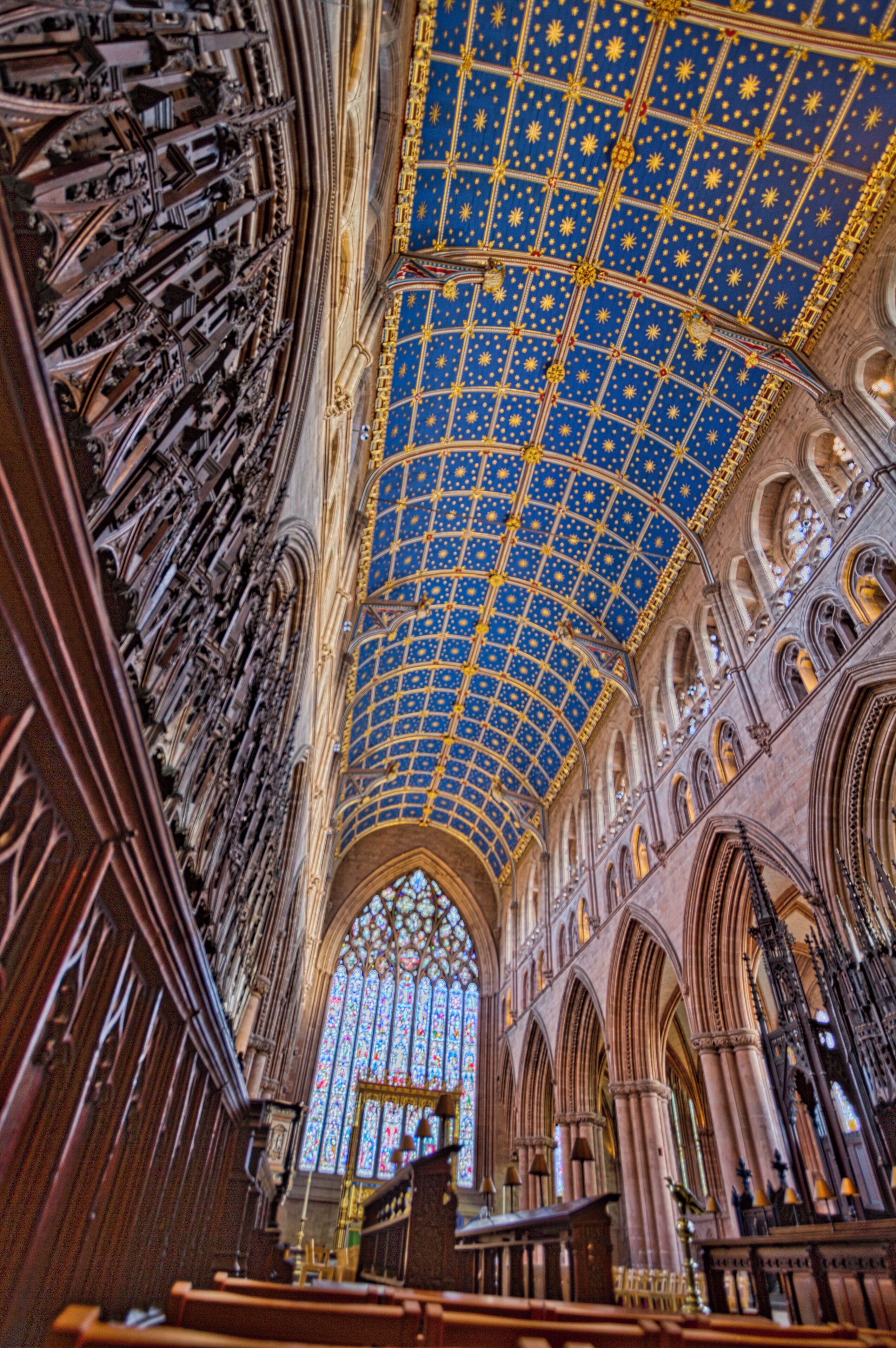 A cathedral interior with a blue star-patterned ceiling and Gothic architecture.