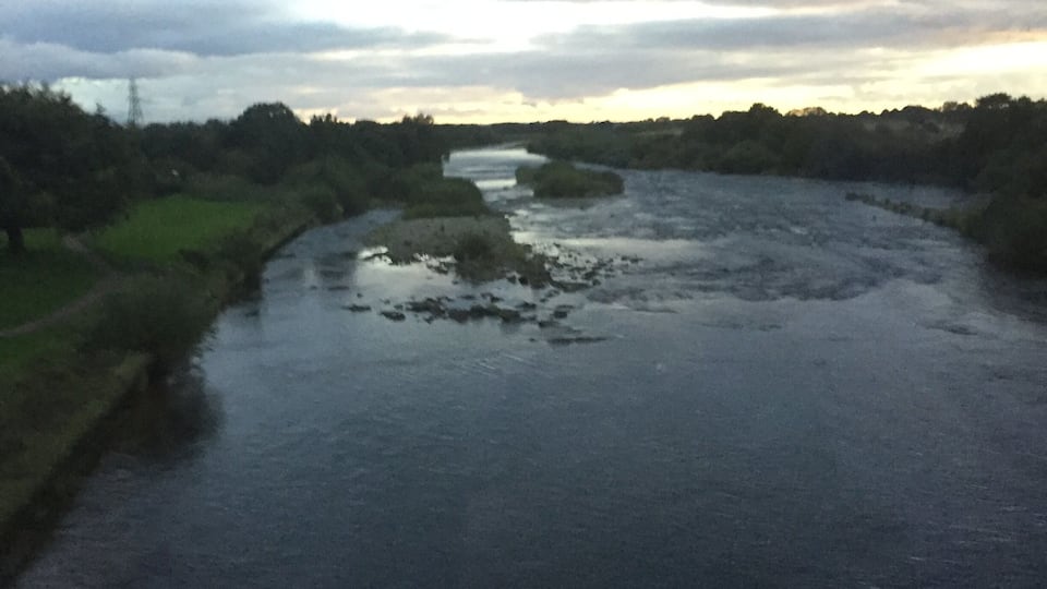 A river with a narrow bridge in the distance.