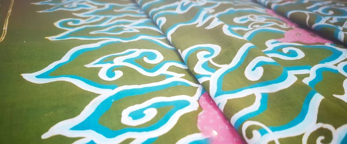 A fabric with a green background and blue and white swirling patterns.