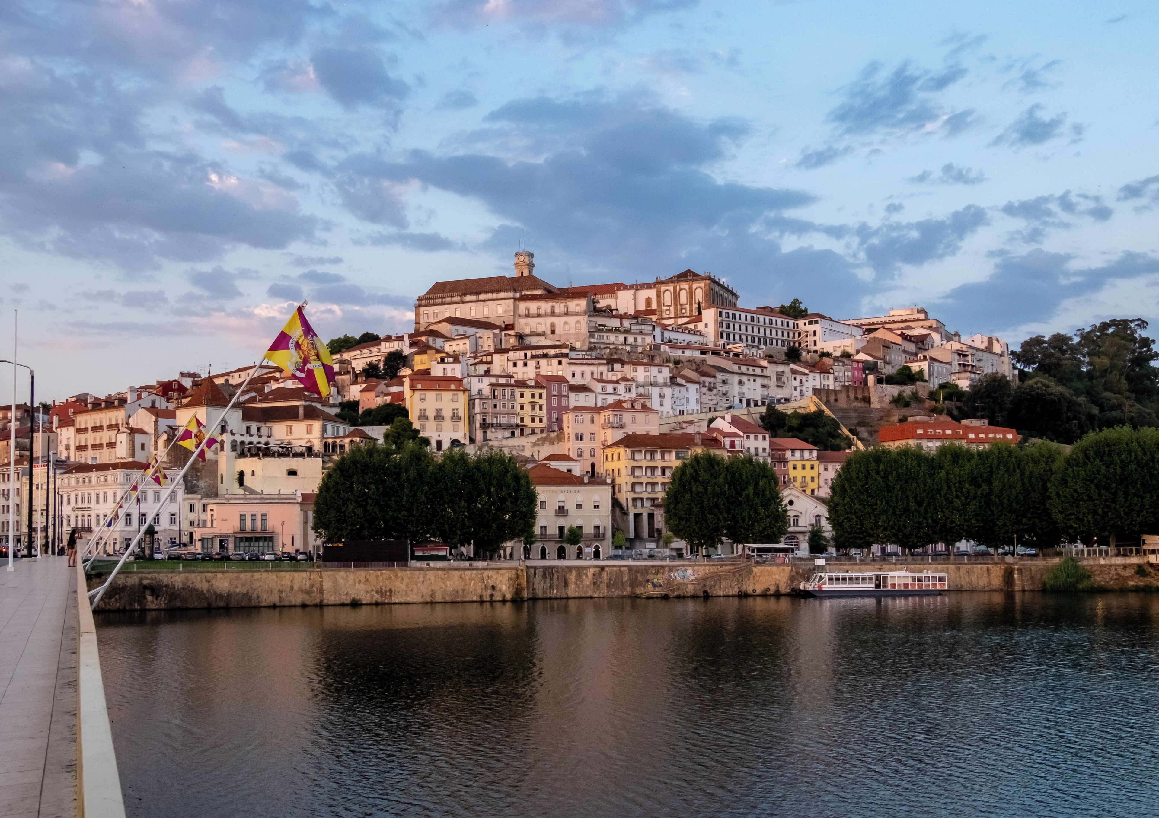 A riverside cityscape with historic buildings, a prominent church, and a flag.