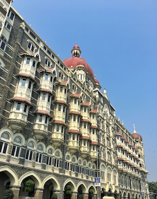 Un bâtiment historique à l’architecture riche et ornée, doté de nombreux balcons et surmonté d’un imposant dôme rouge.