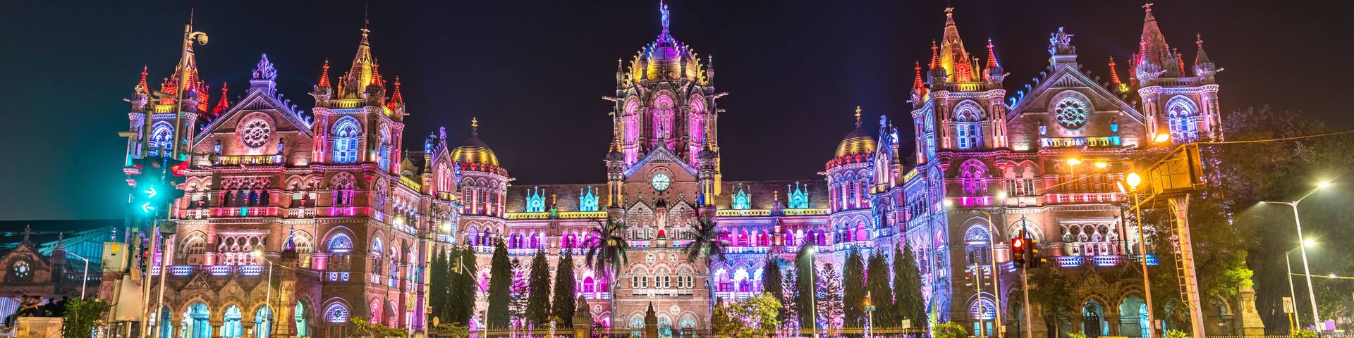 A brightly lit historic building with multiple spires and arches, surrounded by a well-maintained plaza.