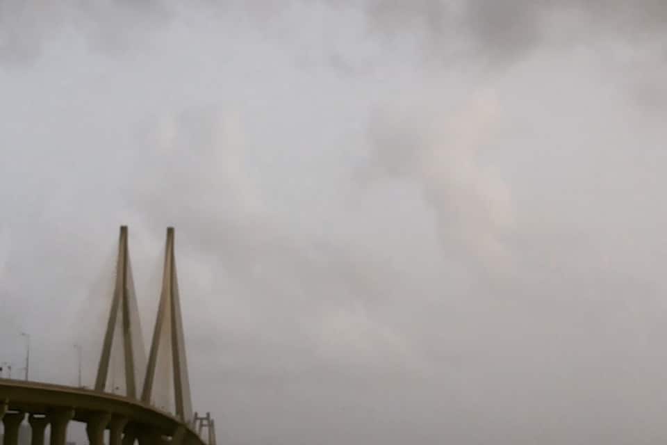 A bridge with two tall pillars and rough sea waves.