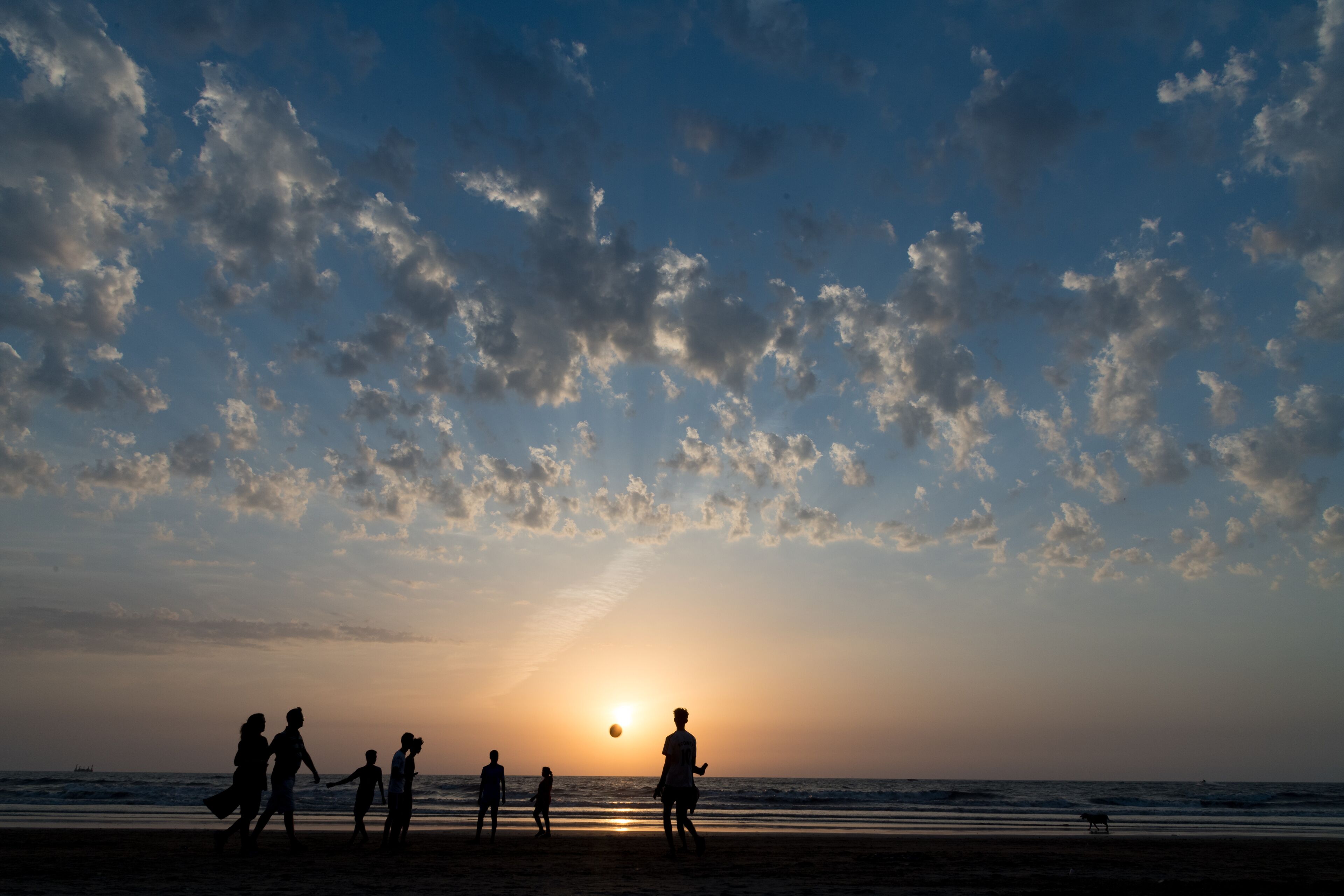 Una playa con gente jugando cerca del agua al atardecer.