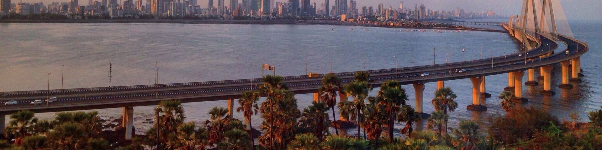 A coastal cityscape with a prominent bridge and palm trees.